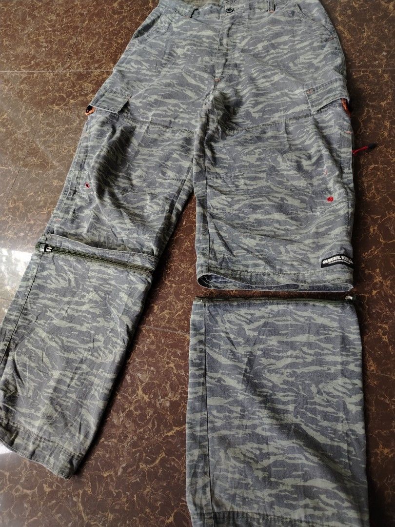 Quiksilver Tiger Camo Zip-off Cargo Pants (Category: Jeans) located in Alegria. Submitted by goofy_ripper (Listing ID 1468374575, Image 2). Description: - Brand: Quiksilver - Style: Grey tiger camouflage cargo pants with versatile zip-off design (converts into shorts) - Features: Multiple functional pockets, stylish red pull cords on zippers and leg cuffs, and signature woven Quiksilver logo patch on the cargo pocket - Closure: Classic button fly