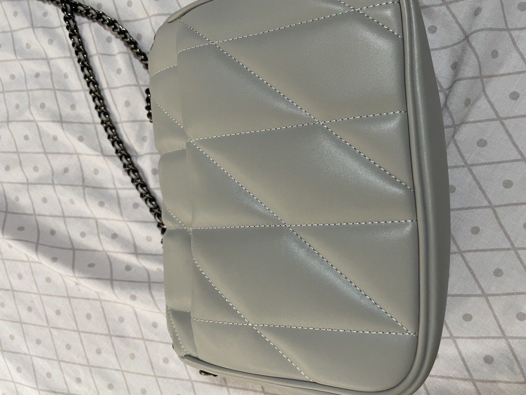 Quilted Grey Crossbody Bag with Chain Strap (Category: Luxury Bags & Wallets) located in Quezon City. Submitted by tor_ash (Listing ID 1468322233, Image 2). Description: - Color: Light grey - Material: Smooth faux leather with chevron stitch detailing - Hardware: Dark gunmetal chain strap and front turn-lock closure - Structure: Boxy and structured shape - Interior: Clean lining with dual chain pass-through grommets - Size: Compact, perfect for d