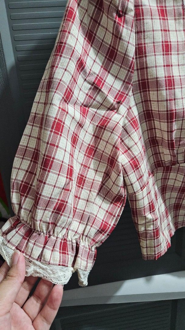 Red White Plaid Square Neck Crop Top Blouse (Category: Blouses) located in Quezon City. Submitted by tiamaureia (Listing ID 1468391932, Image 3). Description: - Design: Red and white plaid pattern with a fitted bodice - Neckline: Square neck with white lace trim and center ruching - Details: Three decorative gold-toned buttons on the front placket - Sleeves: Puff sleeves with elasticized ruffled cuffs and lace trim - Fit: Cropped length, lightwei