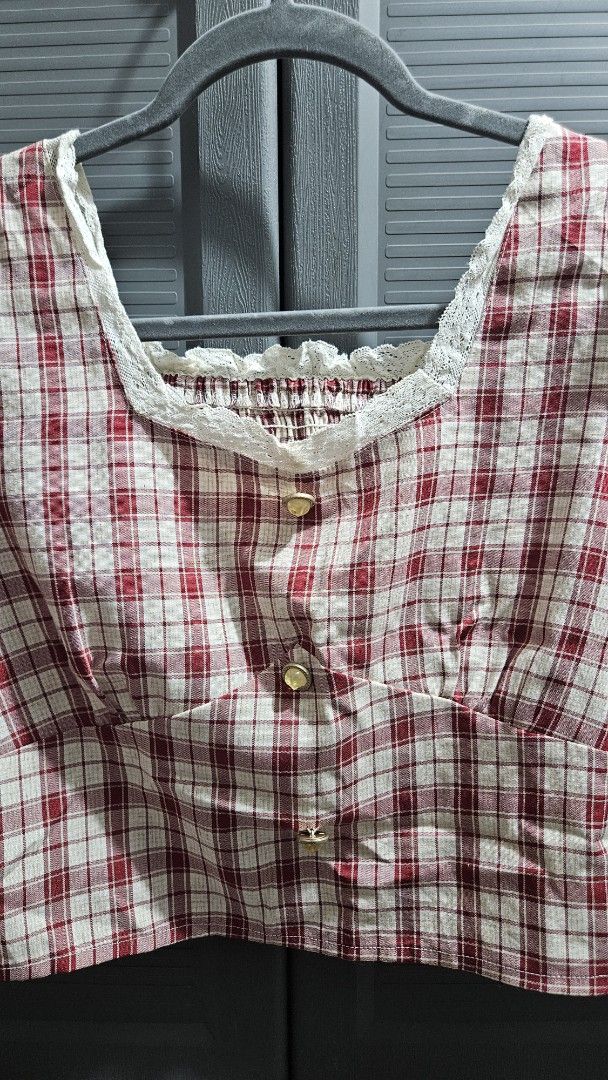 Red White Plaid Square Neck Crop Top Blouse (Category: Blouses) located in Quezon City. Submitted by tiamaureia (Listing ID 1468391932, Image 2). Description: - Design: Red and white plaid pattern with a fitted bodice - Neckline: Square neck with white lace trim and center ruching - Details: Three decorative gold-toned buttons on the front placket - Sleeves: Puff sleeves with elasticized ruffled cuffs and lace trim - Fit: Cropped length, lightwei