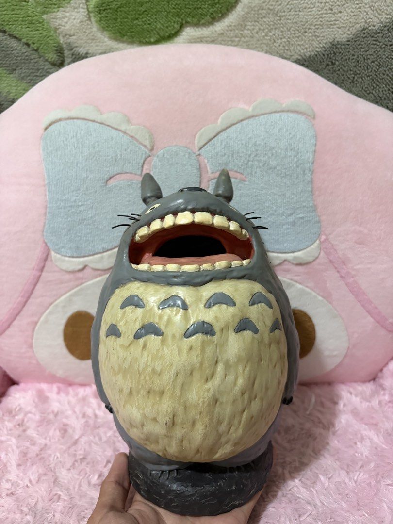 Roaring totoro coin bank (Category: Figurines & Statues) located in Naic. Submitted by rmcollectibles (Listing ID 1468437475, Image 1). Description: - Authentic Grey Totoro figurine featuring a playful wide-open mouth and detailed teeth - Textured furry belly and distinct whiskers for an accurate Studio Ghibli look - Classic two pointy ears on top (minor paint chip on the tip of one ear) - Stands upright firmly on a sleek dark base - Highly detai