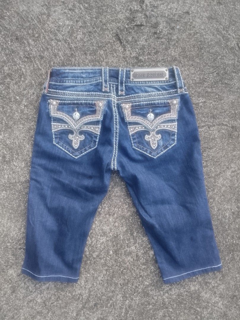 Rock Revival "Celine" Capri Jeans, Size 28 (Category: Jeans) located in Manila. Submitted by tjlee24 (Listing ID 1468496375, Image 3). Description: 👖 Style: Capri cut, fleur-de-lis embroidered flap pockets with rhinestone accents 🎨 Color: Dark wash blue denim 🧵 Material: Denim, two-tone contrast stitching (white/tan), crystal detailing 📏 Size: 28 (US) — roughly Philippine size 26–27/S waist 🏷️ Brand: Rock Revival, Made in China ✅ Condition: 
