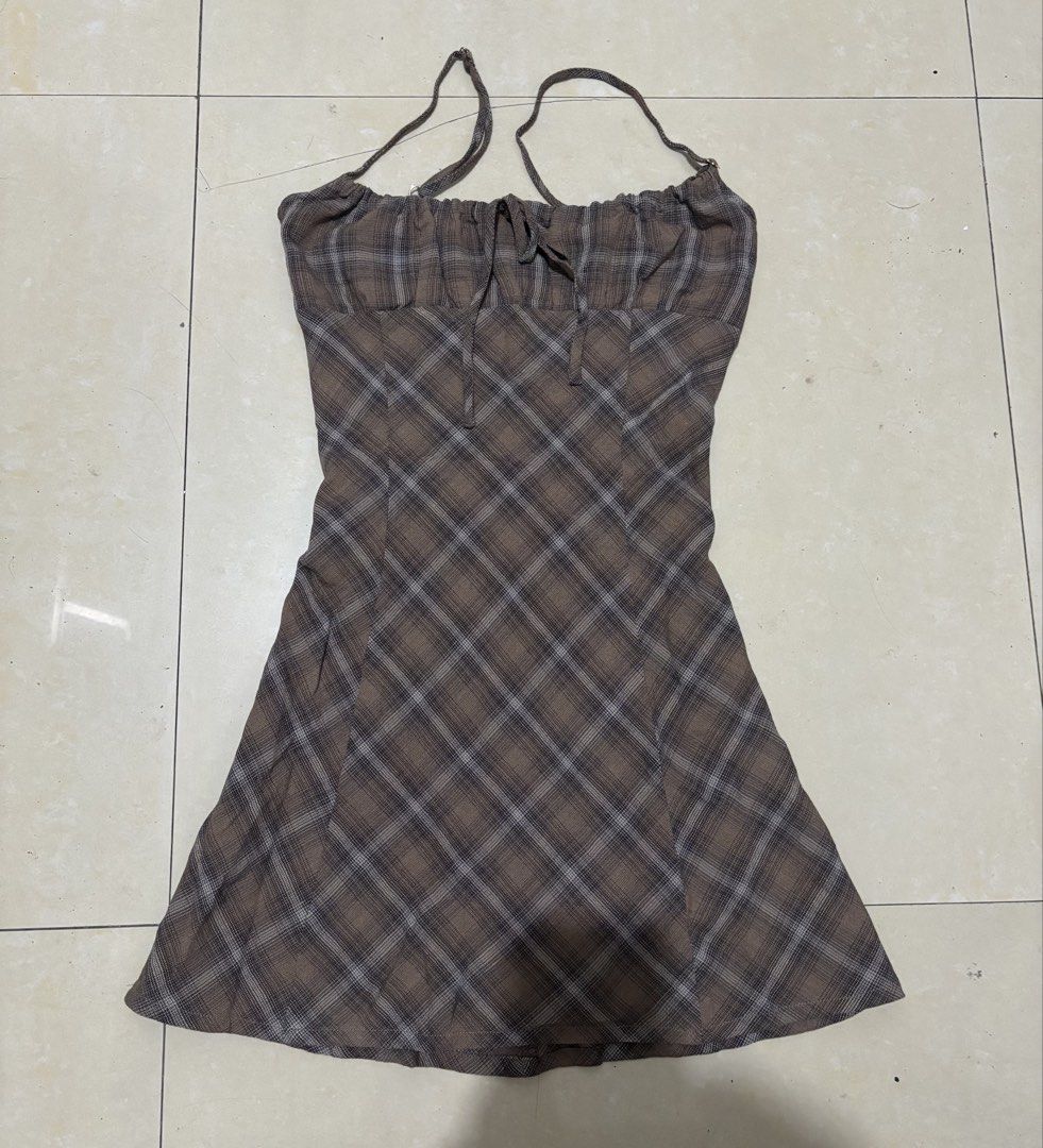Romi Studios Brown Plaid Halter Mini Dress (Category: Dresses) located in Manila. Submitted by van390867 (Listing ID 1468411551, Image 1). Description: - Brand: Romi Studios Size: XS - Style: Brown plaid mini dress with a flared skirt shape - Details: Ruched bustline with adjustable tie string and thin straps - Fit: Zipper-free, slip-on design, fully lined inside - Occasion: Ideal for casual outings, malling, or date nights.