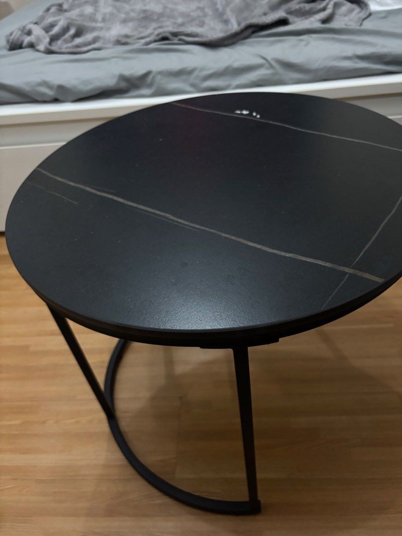 Round Black Coffee Table with Metal Frame (Category: Tables & Sets) located in Cavite. Submitted by xxjxt (Listing ID 1468403904, Image 1). Description: - Type: Round coffee table - Dimensions: Approx. 1 meter across - Materials: Dark stone-pattern top with sturdy black metal base and semi-circular legs - Condition: Noticeable surface wear, light scratches, water rings, and minor paint chipping near the edge; structurally solid - Ideal for: Livin