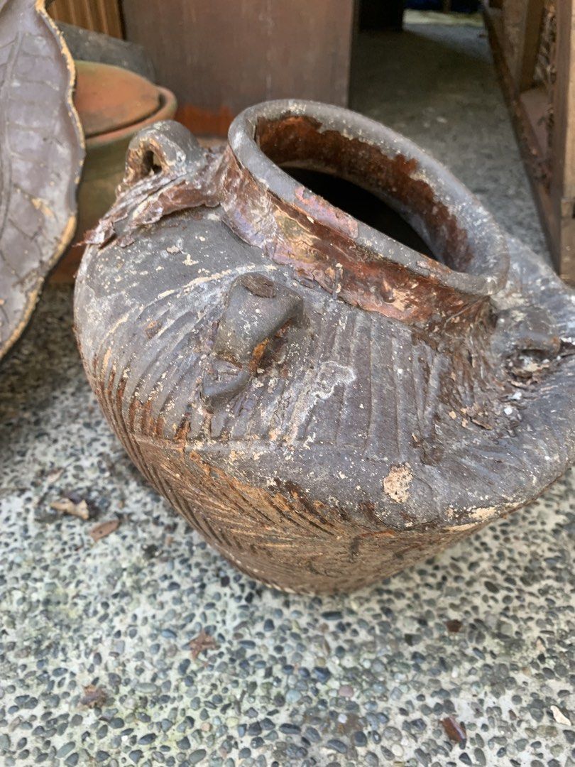 Rustic textured ceramic jar with handles (Category: Vases & Decorative Bowls) located in Quezon City. Submitted by sojisup (Listing ID 1468314126, Image 1). Description: - Material: Solid earthenware with dark brown glaze - Design: Earth-toned with decorative vertical carvings and built-in side handles - Features: Open top rim with slightly flared lip and heavy base - Condition: Rustic texture showing natural aging, patina, and minor chips - Idea