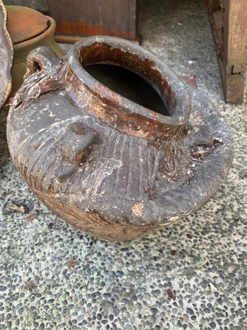 Rustic textured ceramic jar with handles (Category: Vases & Decorative Bowls) located in Quezon City. Submitted by sojisup (Listing ID 1468314126, Image 2). Description: - Material: Solid earthenware with dark brown glaze - Design: Earth-toned with decorative vertical carvings and built-in side handles - Features: Open top rim with slightly flared lip and heavy base - Condition: Rustic texture showing natural aging, patina, and minor chips - Idea