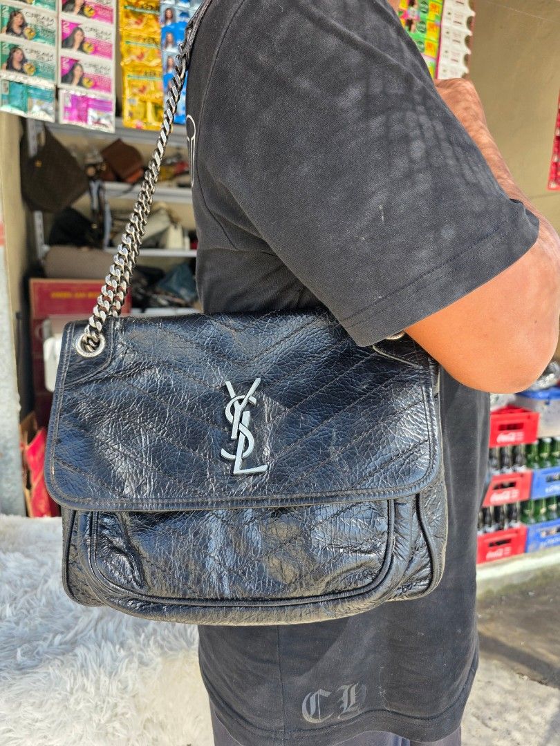 Saint Laurent Black Leather Chain Bag (Category: Shoulder Bags) located in Lemery. Submitted by venus23 (Listing ID 1468306614, Image 2). Description: Black crinkled leather shoulder bag from Saint Laurent. Features quilted chevron pattern and silver-tone hardware. YSL monogram logo on the front flap. Chain strap with leather shoulder guard. Magnetic snap closure engraved with Saint Laurent Paris branding. Metal grommets with etched brand text..