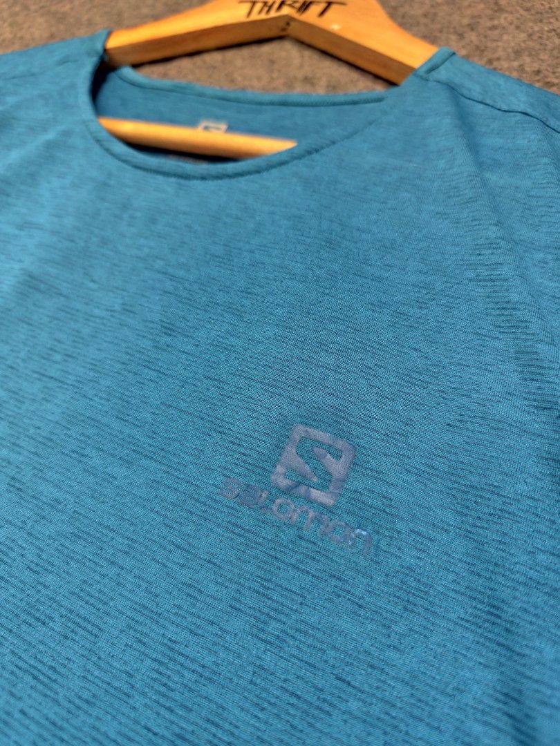 Salomon Blue Active Tech Tee (Category: Activewear) located in Cordova. Submitted by bsb.streetluxvintage.clothing (Listing ID 1468424693, Image 2). Description: - Brand: Salomon - Color: Bright blue with subtle heathered texture - Size: Medium - Material: 100% polyester with 37.5 tech for quick drying and moisture management - Features: Short sleeves, crew neck, and chest logo - Condition: Clean, inside and out - Ideal for: Running, hiking, and 