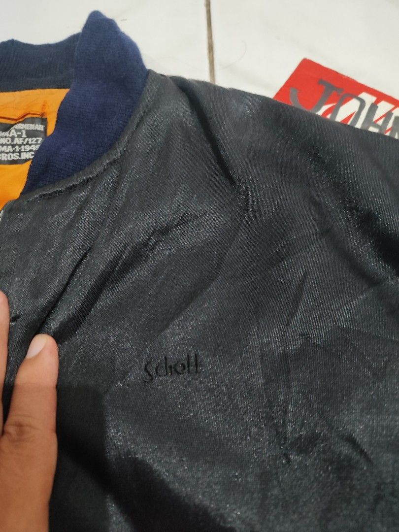 Schott Bros. Inc. Type MA-1 Bomber Jacket (Category: Coats, Jackets and Outerwear) located in Tuguegarao City. Submitted by johnpetera0818 (Listing ID 1468471288, Image 3). Description: - Brand: Schott Bros. Inc. - Model: Type MA-1 Flight Jacket - Color: Classic black with high-vis orange lining - Trim: Dark blue ribbed collar, cuffs, and hem - Pockets: Zippered sleeve utility pocket and snap button waist pockets - Branding: Schott embroidered lo