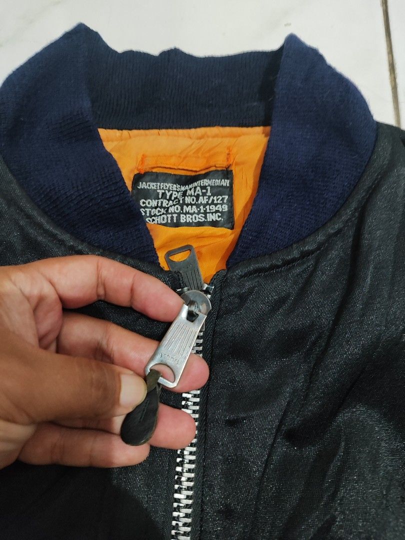 Schott Bros. Inc. Type MA-1 Bomber Jacket (Category: Coats, Jackets and Outerwear) located in Tuguegarao City. Submitted by johnpetera0818 (Listing ID 1468471288, Image 2). Description: - Brand: Schott Bros. Inc. - Model: Type MA-1 Flight Jacket - Color: Classic black with high-vis orange lining - Trim: Dark blue ribbed collar, cuffs, and hem - Pockets: Zippered sleeve utility pocket and snap button waist pockets - Branding: Schott embroidered lo