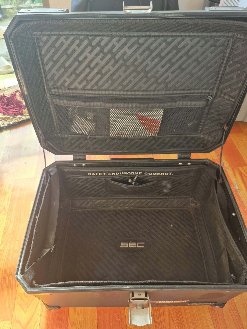 SEC TOP BOX HEXALITE 65L (Category: Body Parts and Accessories) located in Cainta. Submitted by roiyd (Listing ID 1468293651, Image 3). Description: - Brand: SEC Motorcycle Top Box - Color: Black - Material: Heavy-duty aluminum-style construction - Security: Secure front metal latch and lock mechanism - Interior: Textured padding, elastic pockets, and a zippered mesh compartment on the lid - Exterior: Sturdy reinforced corners and top-lid tie-dow