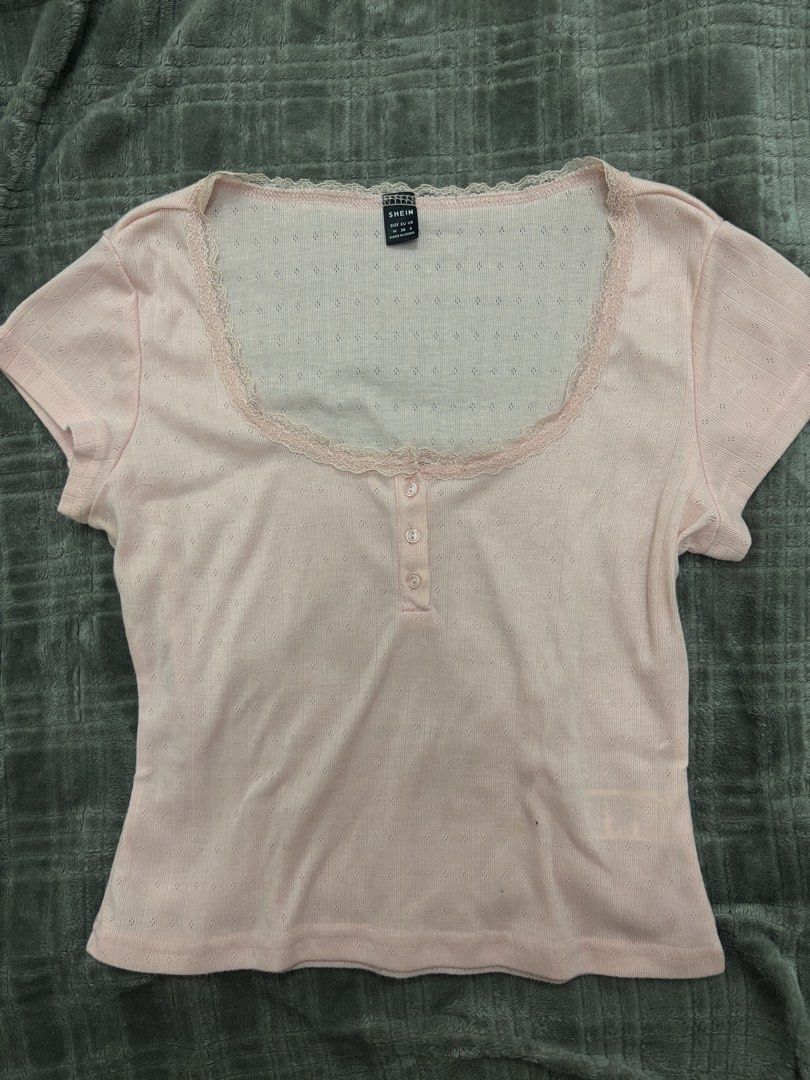 SHEIN Pink Lace Trim Button Top Size M (Category: Shirts) located in Cavite. Submitted by xxjxt (Listing ID 1468407650, Image 1). Description: - Brand: SHEIN - Size: M-L - Color: Pastel Pink - Neckline: Scoop neck with delicate lace trim - Details: Three front buttons, textured diamond pointelle knit pattern - Material: Soft fabric with standard stretch - Condition: Clean inside and out - Styling: Great for pairing with high-waisted jeans or skir
