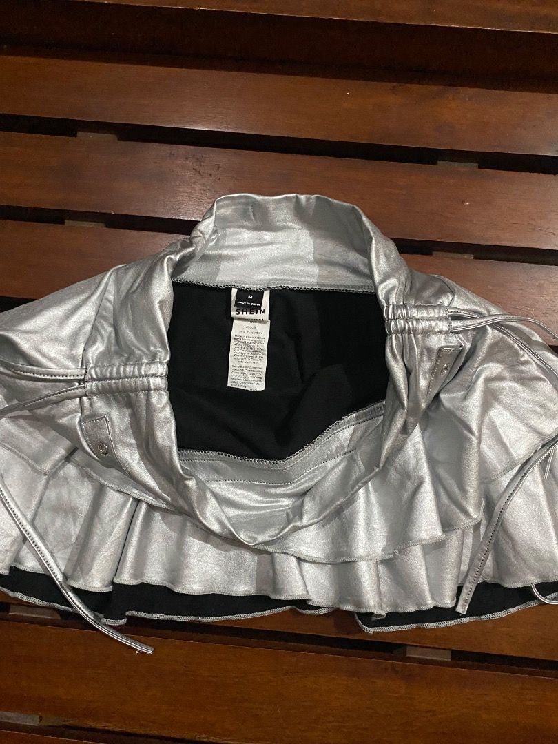 SHEIN Silver Metallic Ruffle Skirt Size M (Category: Skirts) located in Pateros City. Submitted by strawberhyun (Listing ID 1468374066, Image 3). Description: - Brand: SHEIN - Size: Medium (M) - Color/Finish: Silver metallic with a shiny finish - Design: Layered ruffle skirt with eyelet waistband and side tie strings - Lining: Comfortable black lining underneath - Material: 93% polyester, 7% elastane - Perfect for: Parties, night outs, and statem