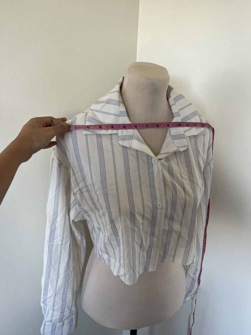 SHEIN Striped Long Sleeve Button-Up Crop Top (Category: Longsleeves) located in Mandaluyong City. Submitted by bravedeer.020ad7 (Listing ID 1468366025, Image 2). Description: - Style: White crop top with blue vertical stripes - Fit: Relaxed fit with a cropped length above the waist - Details: Long sleeves, spread collar, front button closure - Material: Lightweight and comfortable fabric.