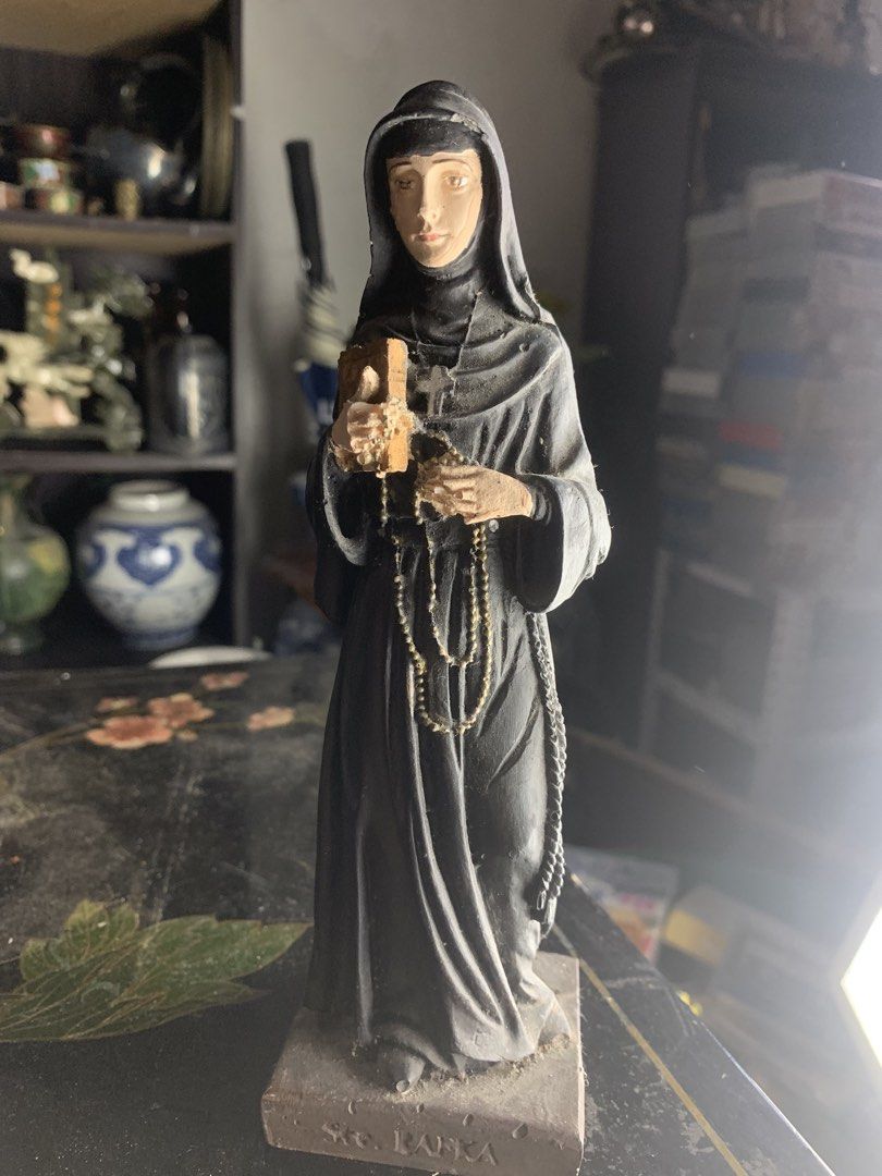 St. Rafka statue nun figurine religious decor (Category: Religious Items) located in Quezon City. Submitted by sojisup (Listing ID 1468325649, Image 1). Description: - Item: St. Rafka Nun Figurine - Appearance: Dressed in a grey habit and veil - Details: Holds a small wooden book and rosary beads - Base: Inscribed with 'Ste. RAFKA' - Condition: Pre-owned display item with some dust accumulation.