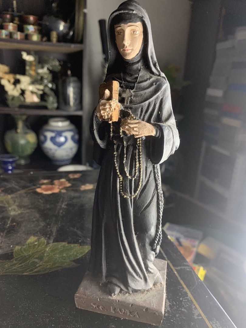 St. Rafka statue nun figurine religious decor (Category: Religious Items) located in Quezon City. Submitted by sojisup (Listing ID 1468325649, Image 3). Description: - Item: St. Rafka Nun Figurine - Appearance: Dressed in a grey habit and veil - Details: Holds a small wooden book and rosary beads - Base: Inscribed with 'Ste. RAFKA' - Condition: Pre-owned display item with some dust accumulation.