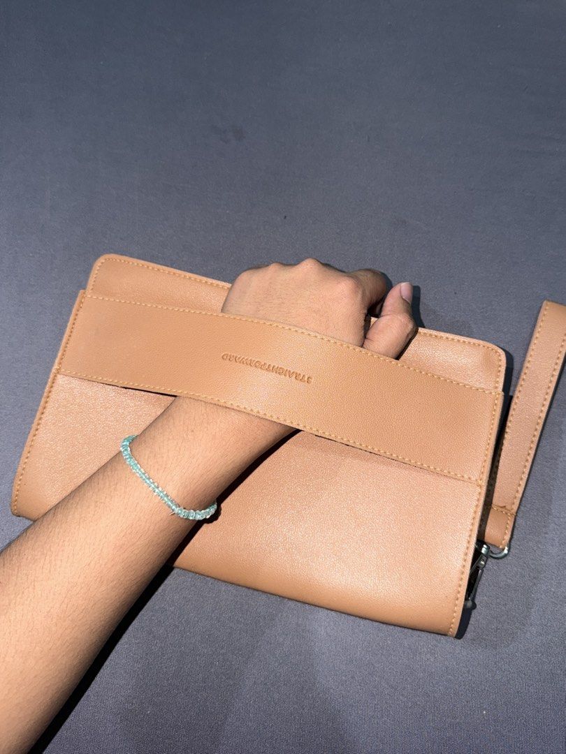 Straightforward Clutch Bag Wristlet (Category: Clutches) located in Quezon City. Submitted by jpfinds (Listing ID 1468436036, Image 2). Description: - Color & Material: Beige faux leather with a clean minimalist design - Branding: Debossed brand logo on the front strap - Hardware & Closure: Secure top zipper closure with silver hardware - Versatility: Includes a detachable wrist strap for easy carrying - Condition: Compact size, ideal for daily e