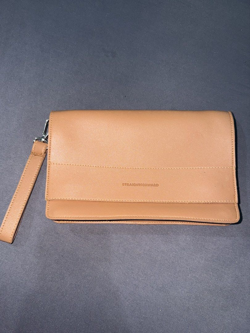 Straightforward Clutch Bag Wristlet (Category: Clutches) located in Quezon City. Submitted by jpfinds (Listing ID 1468436036, Image 1). Description: - Color & Material: Beige faux leather with a clean minimalist design - Branding: Debossed brand logo on the front strap - Hardware & Closure: Secure top zipper closure with silver hardware - Versatility: Includes a detachable wrist strap for easy carrying - Condition: Compact size, ideal for daily e