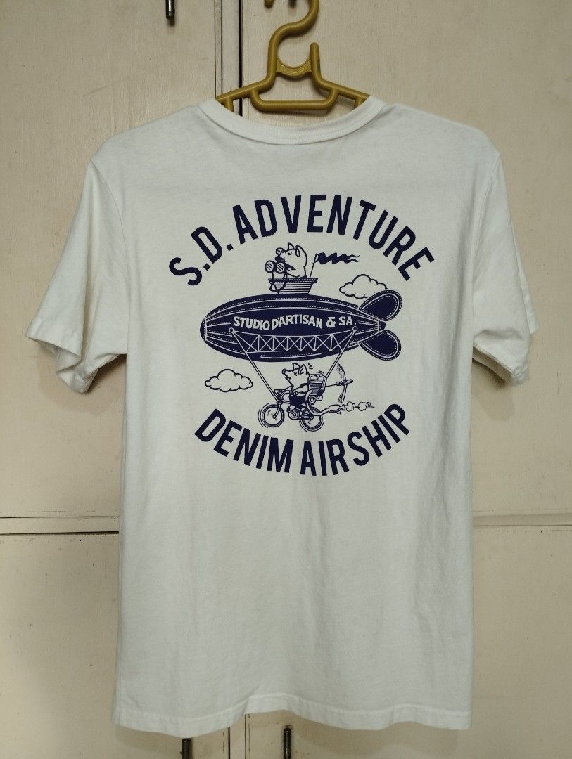 Studio D'Artisan (Category: Tshirts & Polo Shirts ) located in San Fernando. Submitted by nerosales (Listing ID 1468349867, Image 2). Description: - Brand: Studio D'Artisan - Origin: Assembled in JAPAN, fabric made in USA, - Color: White - Graphic: 'S.D. Adventure Denim Airship' design with a pig piloting an airship (front and back) - Ideal for: Studio D'Artisan enthusiasts Small: 17 x 25.5 inches Upper tag is cut. Intact yung dalawang tag sa bab