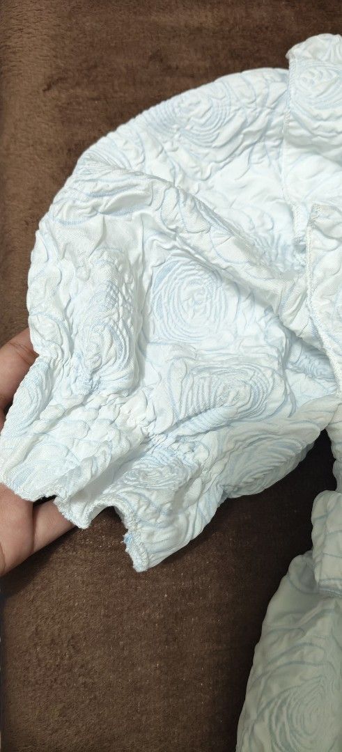 Three Princess Blue Textured Floral Blouse (Category: Blouses) located in Manila. Submitted by snz_shop (Listing ID 1468472570, Image 3). Description: - Brand: Three Princess - Color: Light Blue - Style: Short-sleeve peplum top with button front - Details: All-over textured floral pattern, ruffle shoulders, and elasticized back strap - Fabric: Lightweight and airy, perfect for warm weather - Condition: Excellent.