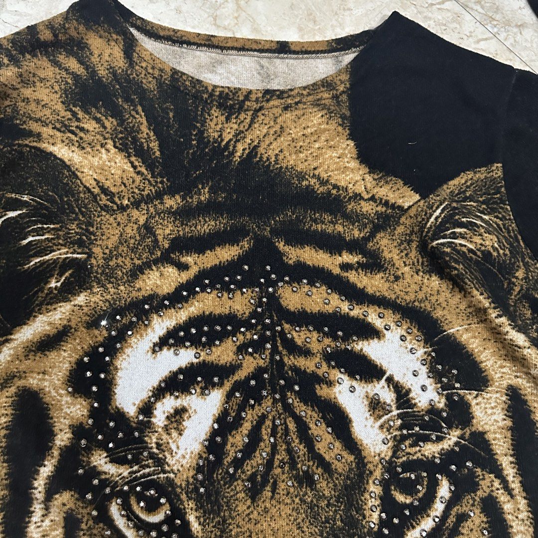 Tiger Print Rhinestone Long Sleeve Sweater (Category: Longsleeves) located in Kawit. Submitted by wevibevintage (Listing ID 1468462737, Image 3). Description: - Design: Bold tiger face graphic with rhinestone accents on stripes and nose - Colors: Black and brown colorway - Fit & Style: Relaxed fit, long sleeves, and round neckline - Material: Soft and comfortable knit fabric - Details: Ribbed black cuffs - Condition: Great statement piece for cas