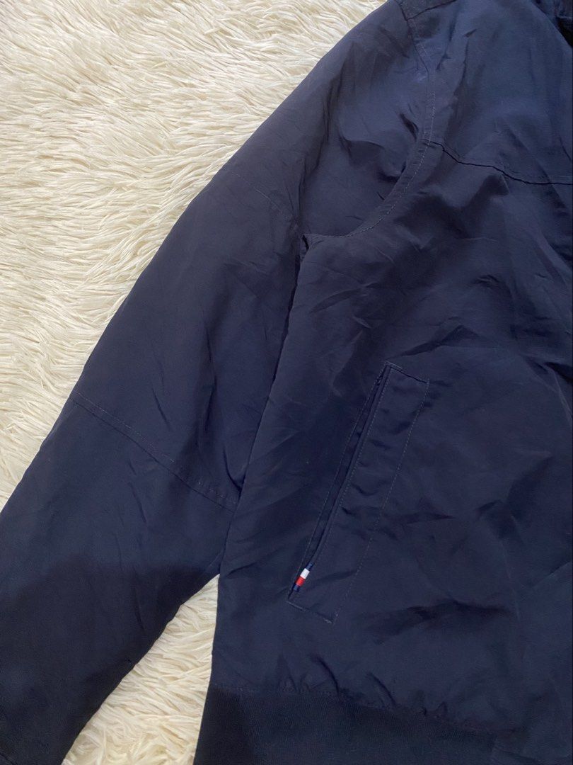 Tommy Hilfiger Navy Blue harrington jacket (Category: Coats, Jackets and Outerwear) located in Antipolo. Submitted by switchneighborhood (Listing ID 1468294776, Image 3). Description: - Brand: Tommy Hilfiger - Color: Dark blue - Material: Lightweight nylon shell with smooth interior lining - Features: Full zip front, stand collar, and ribbed cuffs and hem to block out the wind - Design: Subtle chest pocket and back collar branding for a clean, cl