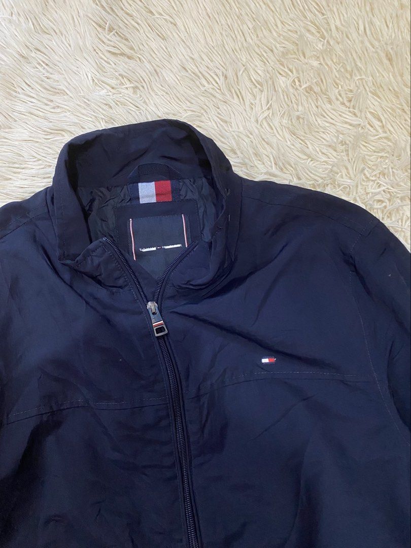Tommy Hilfiger Navy Blue harrington jacket (Category: Coats, Jackets and Outerwear) located in Antipolo. Submitted by switchneighborhood (Listing ID 1468294776, Image 2). Description: - Brand: Tommy Hilfiger - Color: Dark blue - Material: Lightweight nylon shell with smooth interior lining - Features: Full zip front, stand collar, and ribbed cuffs and hem to block out the wind - Design: Subtle chest pocket and back collar branding for a clean, cl