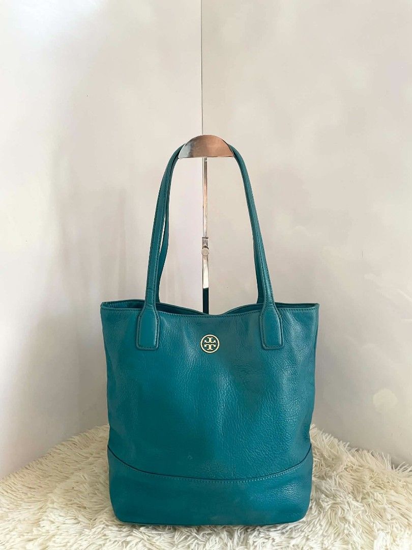 Tory Burch Teal Pebbled Leather Tote Bag (Category: Tote Bags) located in Digos. Submitted by chicandglowbargains (Listing ID 1468070858, Image 2). Description: - Brand: Tory Burch - Material: Premium teal pebbled leather - Hardware: Gold-tone double-T logo on front - Straps: Comfortable double shoulder straps with structured drop - Interior: Spacious with a decorative floral and vine pattern, plus an interior zip pocket - Base: Structured base p