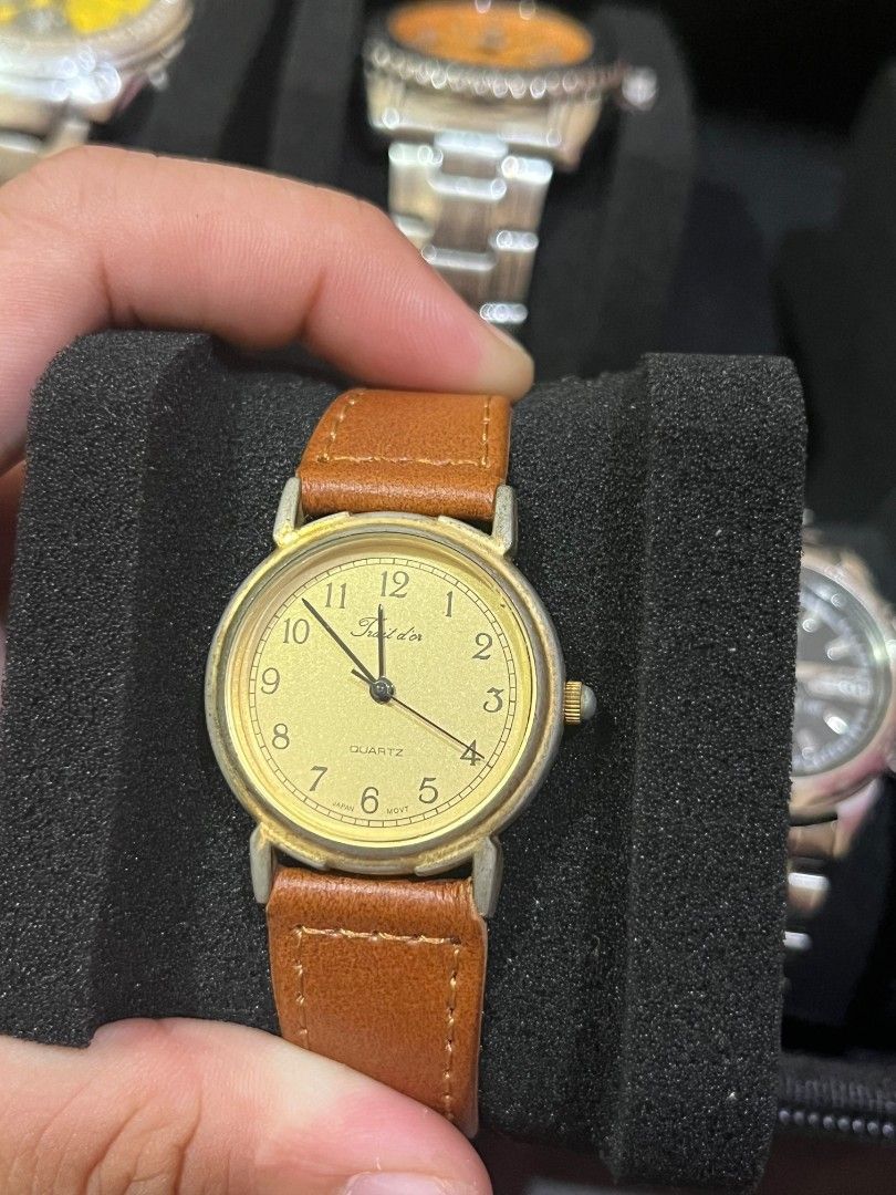 Trait d'or Quartz Gold Dial Watch Brown Leather Strap (Category: Women's Watches) located in Manila. Submitted by kylebalido25364 (Listing ID 1468325227, Image 1). Description: - Brand: Trait d'or - Movement: Japan movement (assembled in China) - Dial: Textured gold with classic Arabic numerals, black hands, and sweep second hand - Case: Two-tone silver and gold stainless steel back with a white stone detail on the crown - Strap: Brown textured l