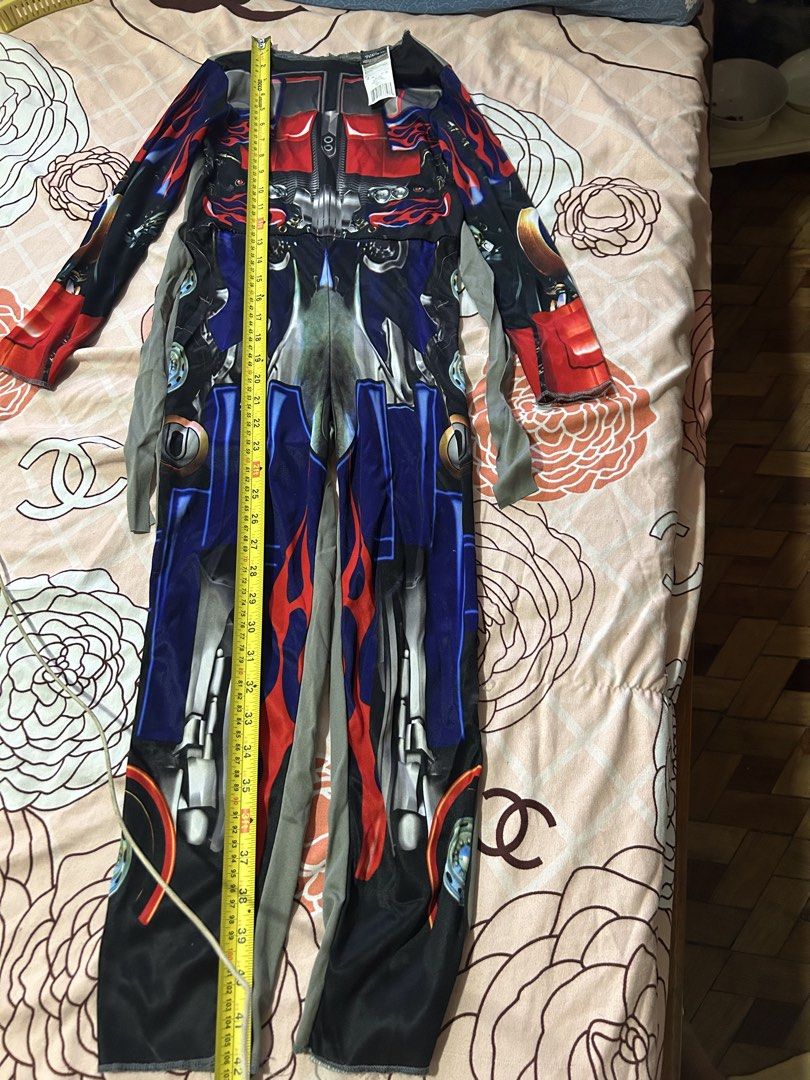 Transformers Optimus Prime Costume Size M 7-8 (Category: Babies & Kids Fashion) located in Meycauayan. Submitted by ms.einz (Listing ID 1468354607, Image 3). Description: - Official Hasbro and DreamWorks licensed Transformers Optimus Prime costume - Size: M (fits kids ages 7-8 years) - Design: Vibrant red, blue, and black full-body print with long sleeves and attached grey fabric ties - Measurements: Approx. 15 inches across chest, 42 inches tota