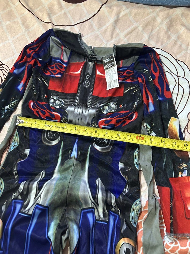 Transformers Optimus Prime Costume Size M 7-8 (Category: Babies & Kids Fashion) located in Meycauayan. Submitted by ms.einz (Listing ID 1468354607, Image 2). Description: - Official Hasbro and DreamWorks licensed Transformers Optimus Prime costume - Size: M (fits kids ages 7-8 years) - Design: Vibrant red, blue, and black full-body print with long sleeves and attached grey fabric ties - Measurements: Approx. 15 inches across chest, 42 inches tota