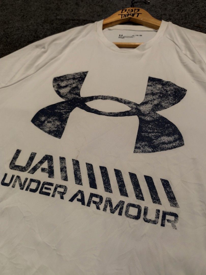 Under Armour Graphic T-Shirt (Category: Activewear) located in Cordova. Submitted by bsb.streetluxvintage.clothing (Listing ID 1468425055, Image 2). Description: - Brand: Under Armour - Size: XL (Loose fit) - Material: 100% polyester - Color: White - Design: Large graphic print with UA branding on the front, small logo near the back collar - Condition: Excellent - Origin: Made in Cambodia.