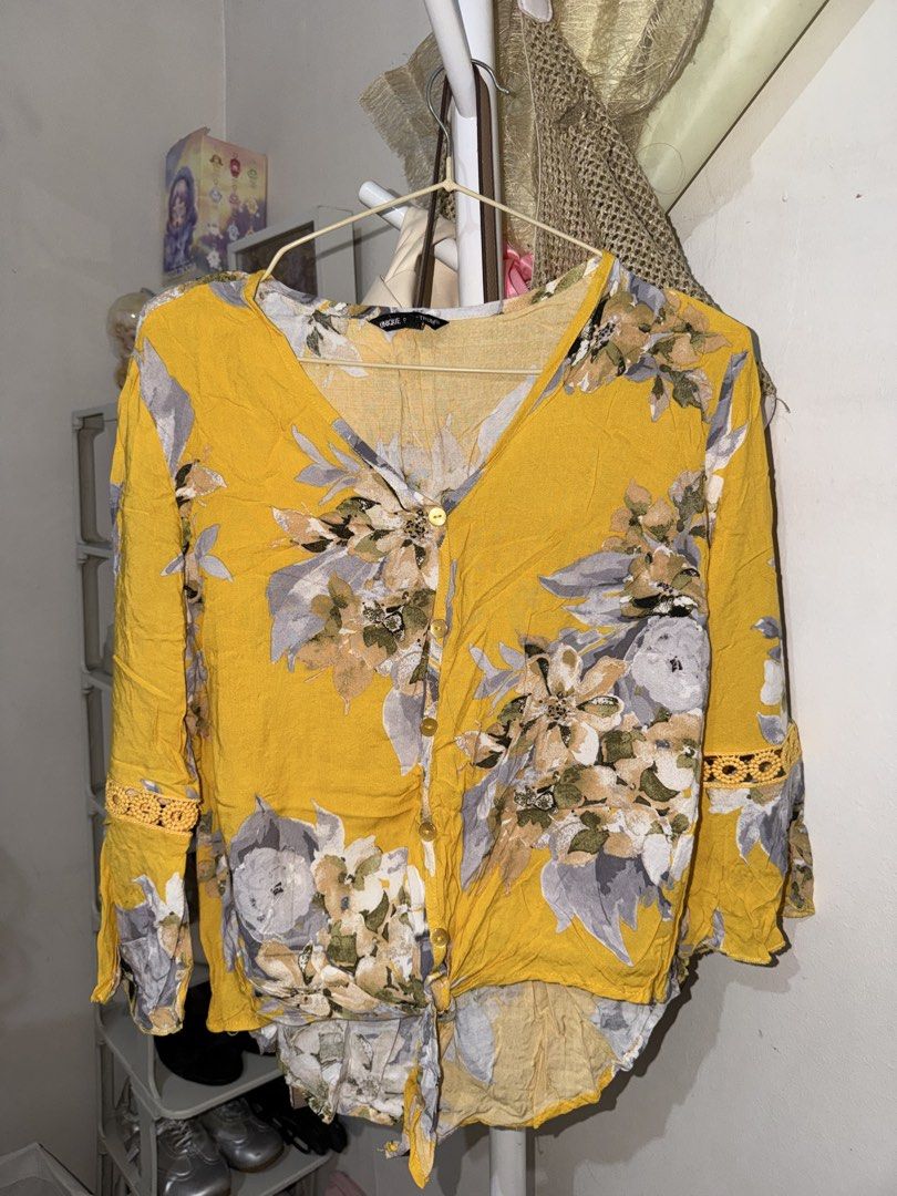 Unique 2 Trump Yellow Floral Button-Down Blouse (Category: Blouses) located in Taguig. Submitted by deguzmanke83356 (Listing ID 1468332545, Image 1). Description: - Color: Bright yellow with grey and white floral pattern - Design: V-neck with front buttons and a cute front hem tie knot - Details: Charming crochet lace inserts on the sleeves - Fabric: Lightweight and breathable, ideal for warm weather - Condition: Excellent, ready to wear.