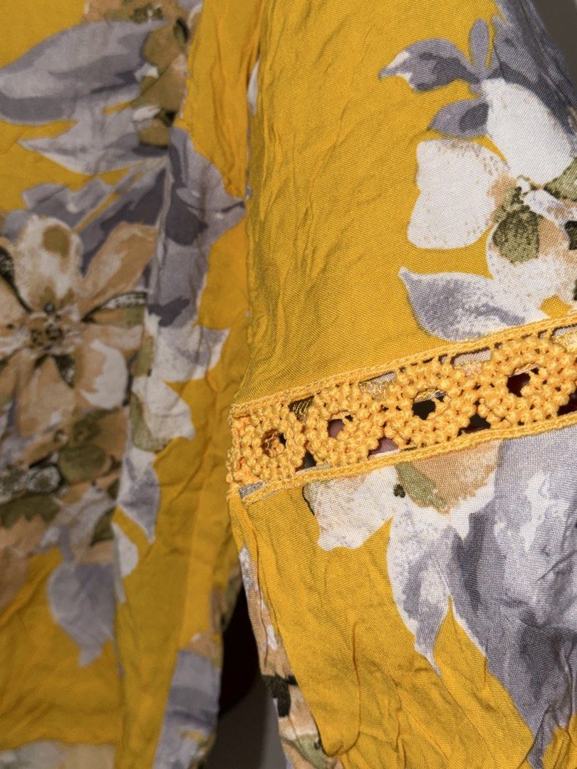 Unique 2 Trump Yellow Floral Button-Down Blouse (Category: Blouses) located in Taguig. Submitted by deguzmanke83356 (Listing ID 1468332545, Image 2). Description: - Color: Bright yellow with grey and white floral pattern - Design: V-neck with front buttons and a cute front hem tie knot - Details: Charming crochet lace inserts on the sleeves - Fabric: Lightweight and breathable, ideal for warm weather - Condition: Excellent, ready to wear.