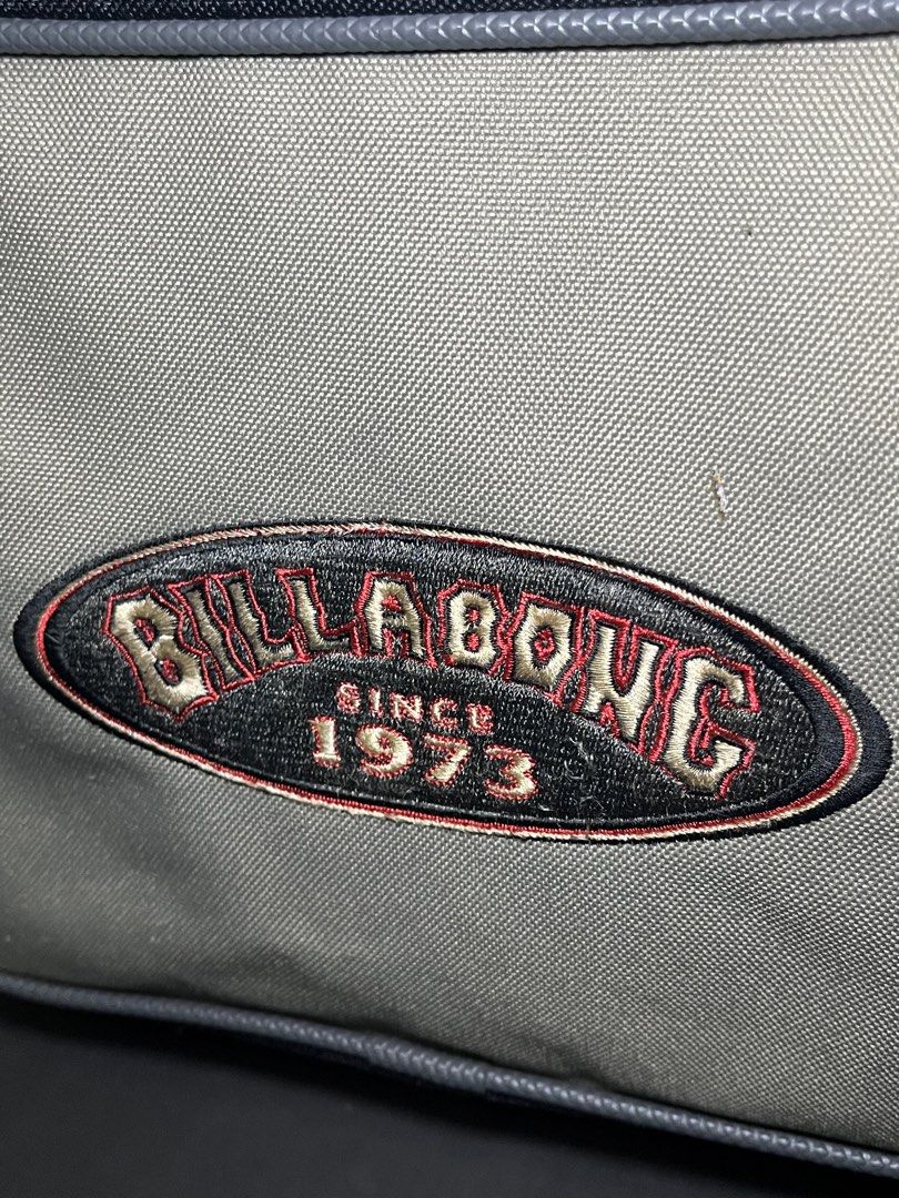 Vintage Billabong 1973 Grey Backpack with Front Pocket (Category: Backpacks) located in Muntinlupa City. Submitted by pastforwardthrift (Listing ID 1468498319, Image 3). Description: - Brand: Billabong - Color: Grey with contrast stitching - Design: Structured rectangular shape with dual 'Billabong Since 1973' embroidered logo patches - Storage: Front zippered pocket for easy access - Features: Sturdy top carry handle and durable woven fabric con