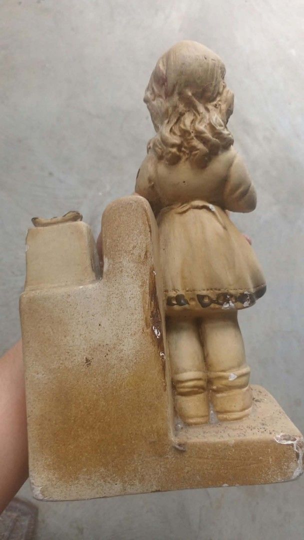 Vintage figurine 1950s era (Category: Figurines & Statues) located in Mandaluyong City. Submitted by LEATHERFACE (Listing ID 1468321475, Image 2). Description: - Vintage-style bookend featuring a young girl with an old-fashioned rotary telephone - Classic neutral beige and brown tones with a rustic finish - Sturdy ceramic construction with a heavy base to securely hold books in place - Authentic weathered aesthetic with noticeable paint chipping 