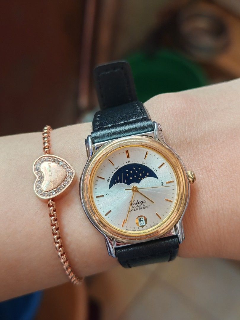 Volcas Quartz Watch Moon Phase Dial Black Leather Strap (Category: Women's Watches) located in Taguig. Submitted by mystuff4youph (Listing ID 1468364501, Image 1). Description: - Brand/Model: Volcas Quartz Watch - Dial: Silver sunburst face with unique moon phase dial and date window at the bottom - Movement: Reliable Japan movement - Design: Gold-toned bezel with stainless steel case back and clean glass - Strap: Black leather strap with a stand