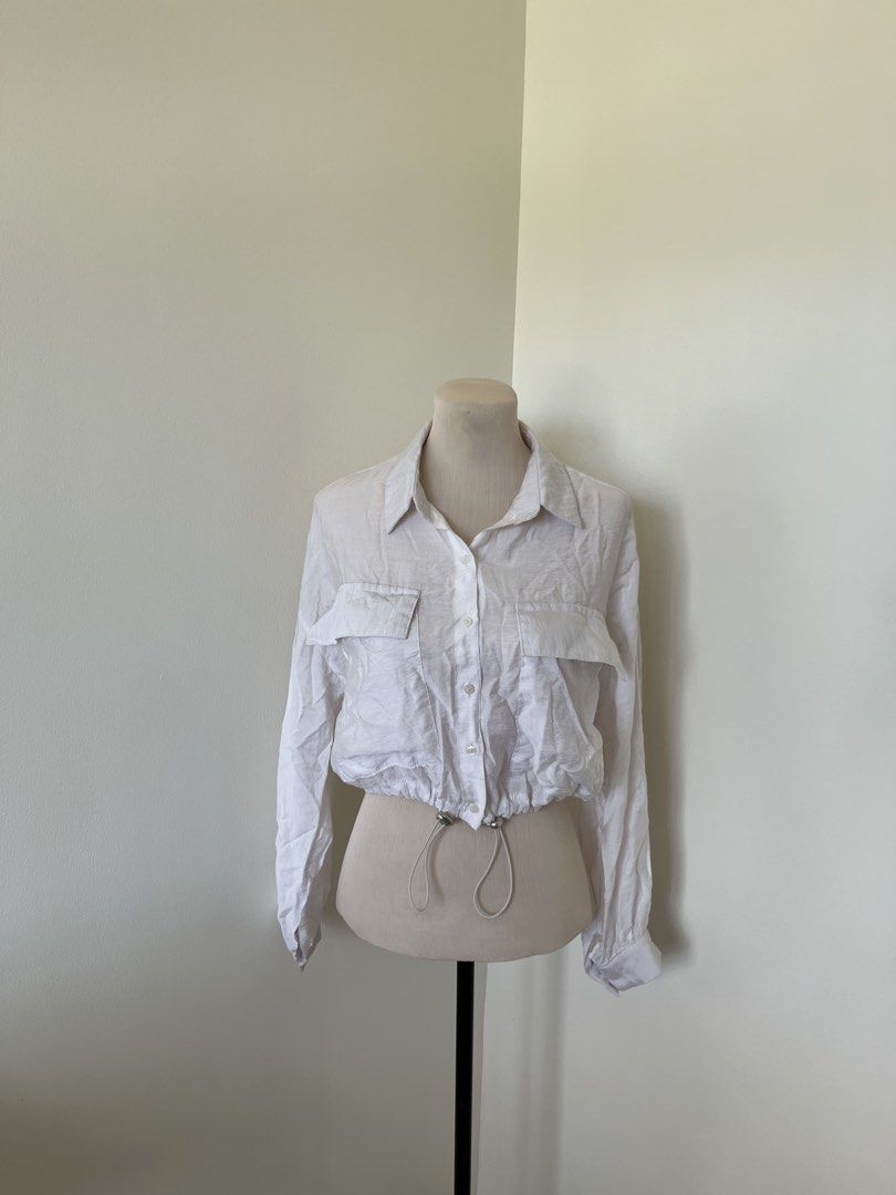 White Long Sleeve Button Down Crop Blouse (Category: Longsleeves) located in Mandaluyong City. Submitted by bravedeer.020ad7 (Listing ID 1468363139, Image 1). Description: - Color: White - Style: Button-down blouse with classic collar - Features: Long sleeves, dual chest pockets, and adjustable drawstring hem with silver hardware - Fabric: Lightweight and comfortable - Condition: Brand new / Excellent (Ready to ship!) .
