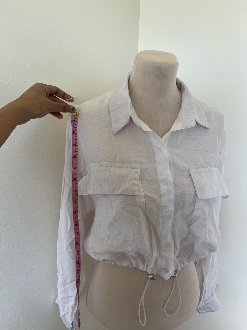 White Long Sleeve Button Down Crop Blouse (Category: Longsleeves) located in Mandaluyong City. Submitted by bravedeer.020ad7 (Listing ID 1468363139, Image 3). Description: - Color: White - Style: Button-down blouse with classic collar - Features: Long sleeves, dual chest pockets, and adjustable drawstring hem with silver hardware - Fabric: Lightweight and comfortable - Condition: Brand new / Excellent (Ready to ship!) .