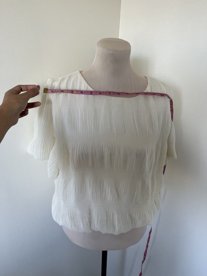 White Pleated Short Sleeve Blouse Round Neck (Category: Blouses) located in Mandaluyong City. Submitted by bravedeer.020ad7 (Listing ID 1468364144, Image 2). Description: - Color: White - Style: Pleated short-sleeve blouse with a rounded neckline - Fabric: Textured crinkle material - Details: Gathered elastic hem - Measurements: Pit-to-pit approx. 13 inches, Length from shoulder to hem approx. 18 inches - Condition: Clean, no stains or holes.