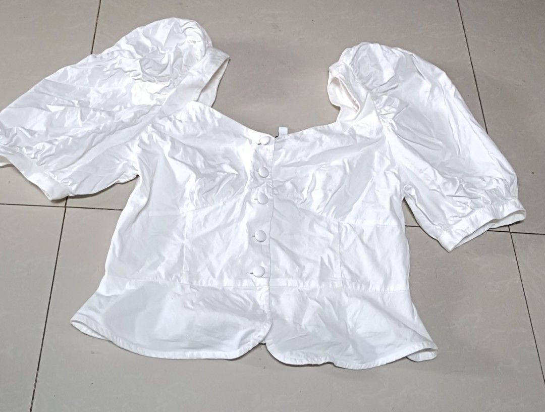 White Puff Sleeve Peplum Blouse with Buttons (Category: Blouses) located in Quezon City. Submitted by davidclothing (Listing ID 1468418879, Image 1). Description: - Color: White - Design: Square neckline with fabric-covered front buttons - Fit: Fitted bodice with a stylish peplum hem - Sleeves: Short, voluminous puff sleeves with gathered shoulders - Material: Lightweight cotton-like fabric.