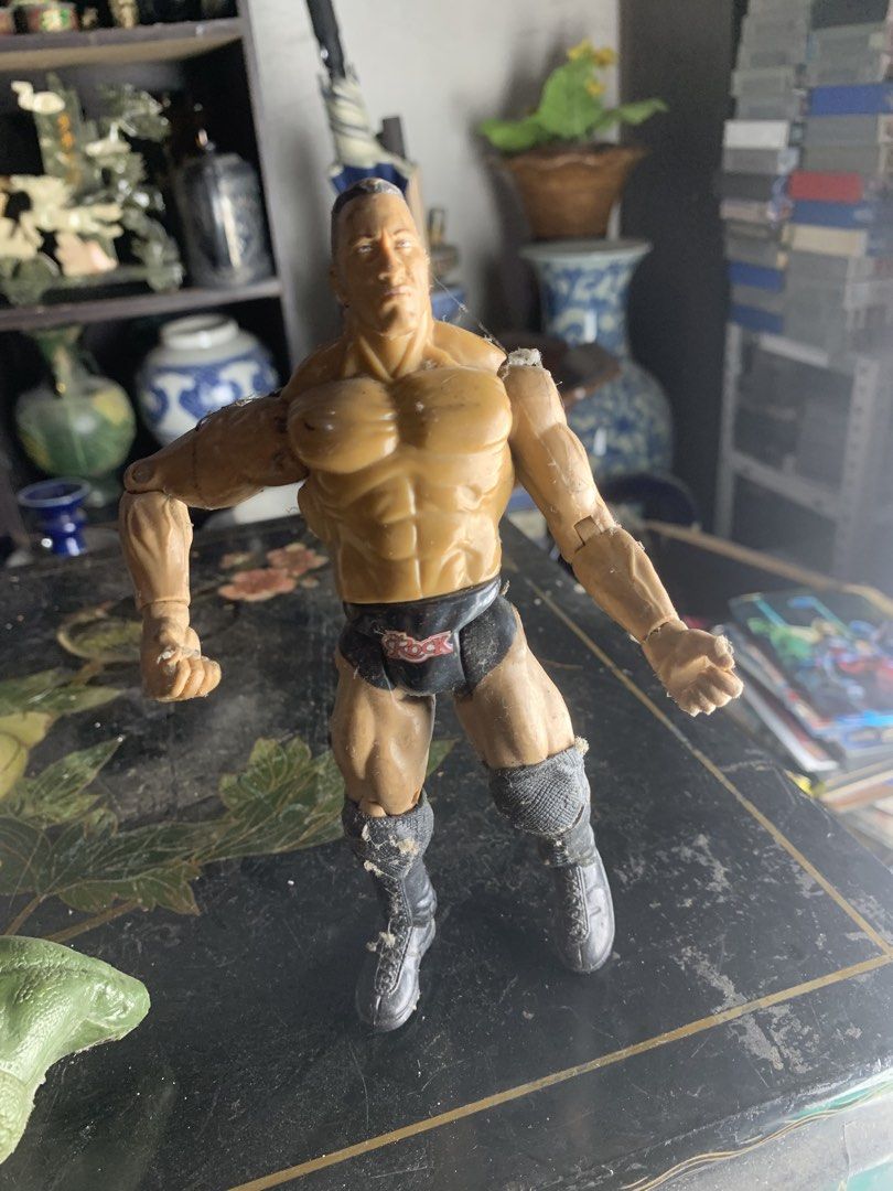 WWE The Rock Action Figure (Category: Figurines & Statues) located in Quezon City. Submitted by sojisup (Listing ID 1468379945, Image 1). Description: - Action figure of The Rock wearing iconic black trunks and matching boots - Articulated arms and legs for easy posing and dynamic display - Stands upright on its own without support - Shows copyright markings and screw fastening on the bottom of the foot - Surface has minor dust and lint from stor