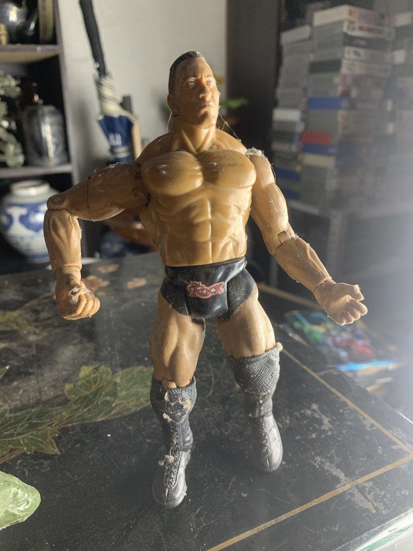 WWE The Rock Action Figure (Category: Figurines & Statues) located in Quezon City. Submitted by sojisup (Listing ID 1468379945, Image 2). Description: - Action figure of The Rock wearing iconic black trunks and matching boots - Articulated arms and legs for easy posing and dynamic display - Stands upright on its own without support - Shows copyright markings and screw fastening on the bottom of the foot - Surface has minor dust and lint from stor