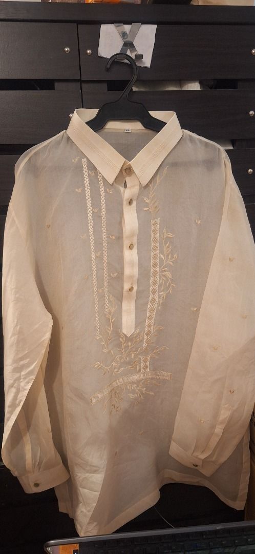 XXL Barong (Category: Formal Shirts) located in General Trias. Submitted by aeunice (Listing ID 1468350956, Image 1). Description: Barong Tagalog Size: XXL In Good Condition. Needs cleaning. Cream-colored Barong Tagalog with intricate embroidery. Features a collared neckline and button-down front. The embroidery is detailed with floral and geometric patterns. Meet up / Shipping via Lalamove, JnT, Gogo Express & LBC..
