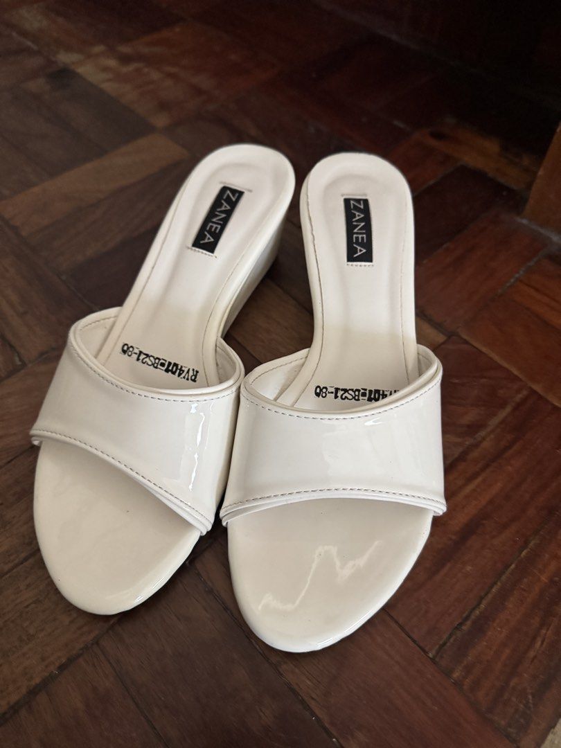Zanea White Patent Wedge Sandals (Category: Wedges) located in Manila. Submitted by chie04_875 (Listing ID 1468400576, Image 2). Description: - Brand: Zanea - Style: Slide-on wedge sandals with comfortable angled heel - Color/Finish: Cream patent with clean white upper straps - Details: Stamped branding on the insole - Condition: Worn only a few times, minimal wear on the soles - Pairing: Easy to match with casual outfits and dresses.