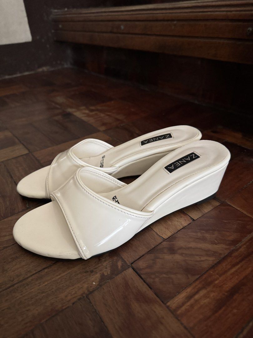 Zanea White Patent Wedge Sandals (Category: Wedges) located in Manila. Submitted by chie04_875 (Listing ID 1468400576, Image 1). Description: - Brand: Zanea - Style: Slide-on wedge sandals with comfortable angled heel - Color/Finish: Cream patent with clean white upper straps - Details: Stamped branding on the insole - Condition: Worn only a few times, minimal wear on the soles - Pairing: Easy to match with casual outfits and dresses.