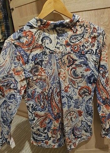 Zara Basic Paisley Print Button-Up Blouse (Category: Blouses) located in Lupao. Submitted by selahthriftedclothing (Listing ID 1468375550, Image 2). Description: - Brand: Zara Basic - Design: White with blue and orange paisley pattern all over - Neckline: V-neck collar - Fabric: Lightweight and comfortable - Versatility: Perfect for casual daily wear or office styling - Pairing: Easy to match with denim or trousers - Siting: Standard sizing.