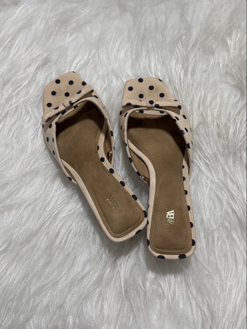 ZARA Beige Polka Dot Mule w Bow (Category: Flats & Sandals) located in Subic. Submitted by juls_mp (Listing ID 1468372223, Image 2). Description: - Brand: ZARA - Style: Slip-on slide sandals - Design: Beige with black polka dots, square toe, and tiny front bow - Details: Suede Material, Brown footbed with gold ZARA logo - Condition: Clean, with minimal signs of wear on the soles - Versatile: Super easy to pair with casual or dressy outfits.
