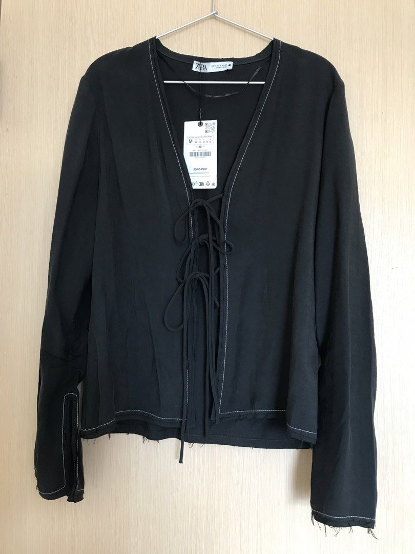 Zara Black Lace-Up Blouse Size M (Category: Blouses) located in Cainta. Submitted by ukaymama (Listing ID 1468295589, Image 1). Description: - Brand: Zara - Size: M (Condition: Brand new with tags) - Color: Black with contrast white stitching - Design: Front lace-up tie closure, long sleeves with slit cuffs, and a trendy raw frayed hem - Material: Lightweight and comfortable fabric.