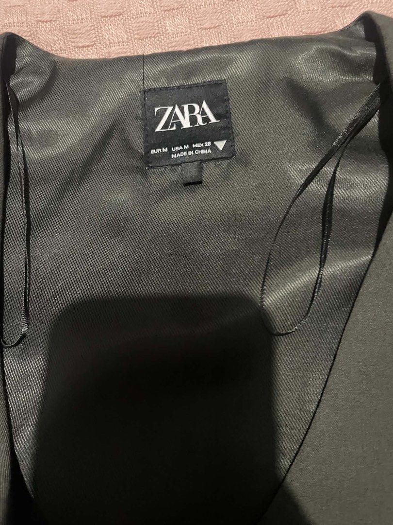 Zara Dark black Suit Vest Size M (Category: Sleeveless) located in Quezon City. Submitted by geohdz (Listing ID 1468309412, Image 2). Description: - Brand: Zara - Size: Medium (M) - Color: black greyish - Closure: Four-button front - Pockets: Two functional welt pockets - Details: Adjustable back strap with silver hardware, fully lined interior - Styling: Classic tailored fit, perfect for layering over shirts or wearing solo.